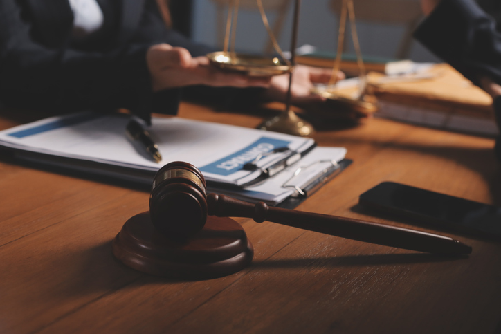 Attraktiv ung advokat i kontorets forretningskvinne og advokater som diskuterer kontraktspapirer med messingskala på trebord i kontoret. Lov, juridiske tjenester, råd, rettferdighet og eiendomskonsept.