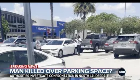 Parkeringsplass med flere kjøretøy, inkludert en hvit sedan som ser ut til å ha vært involvert i en hendelse, som indikert av "Breaking News"-overlegget.