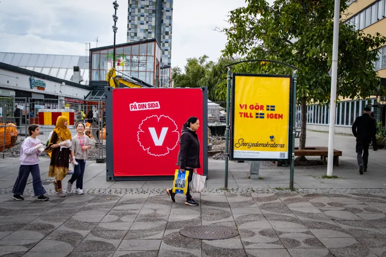 En plakat for Vänsterpartiet (V) og Sverigedemokraterna (H) står side om side i Stockholm-forstaden Tensta