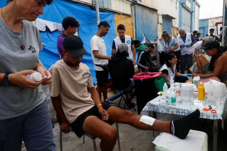 Medlemmer av en spansk frivillig organisasjon Medicos del Mundo (verdens leger) hjelper skadde migranter i et industriområde, etter massekryssingen av migranter fra Marokko, i Ceuta, Spania, 21. september 2026. REUTERS/Jon Nazca