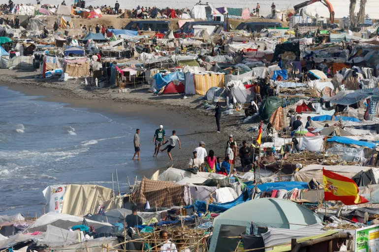 Migranter leker med en ball omgitt av telt ved Trampolin-stranden, etter massekryssingen av migranter fra Marokko i Ceuta, Spania, 19. september 2026. REUTERS/Jon Nazca TPX-BILDER AV DAGEN
