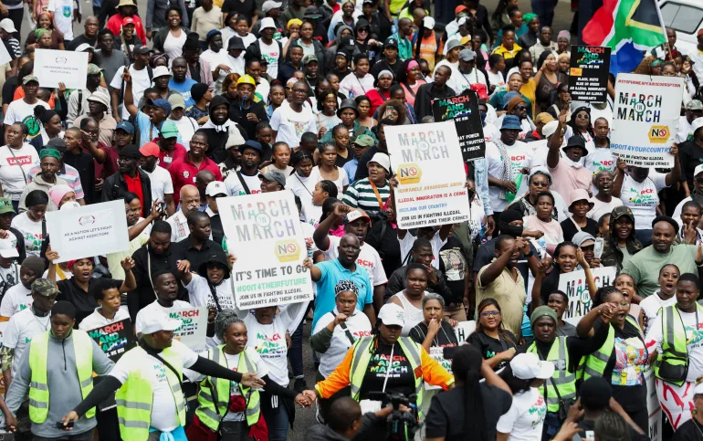 Demonstranter holder plakater under en anti-immigrasjonsmarsj i Durban, Sør-Afrika, der de ber om strengere grensekontroll og deportering av papirløse migranter (Thuli Dlamini/Reuters)