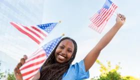 Ung kvinne feirer Amerika med viftende flagg utendørs