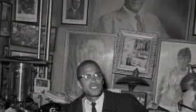 Malcolm X sitter på dekorert kontor